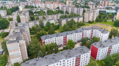 Ağaçlar ve yeşilliklerle çevrili birden fazla apartmanı olan bir doğu Avrupa yerleşim bölgesinin havadan görünüşü.