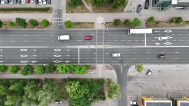 Çevresi yeşillik ve binalarla çevrili, birden fazla şerit ve araçla dolu işlek bir şehir kavşağının havadan görüntüsü. Yol işaretleri ve trafik akışı yukarıdan açıkça görülüyor..