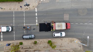 Şehir caddesinde işçilerle ve araçlarla yol onarımının havadan görüntüsü.