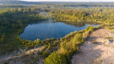 Bereketli yeşillik ve kumlu bir alanla çevrili sakin bir orman gölü..