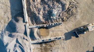 Büyük bir moloz yığını ve buldozerle bir inşaat alanının havadan görüntüsü..