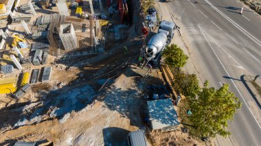 Çimento karıştırıcı kamyonu ve işçileri olan bir inşaat alanının havadan görüntüsü..