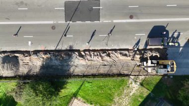 Makine ve işçilerle yol yapımının havadan görüntüsü.