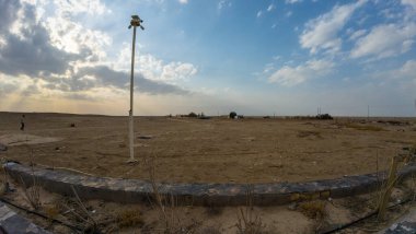 Uçsuz bucaksız, çorak bir çöl manzarası Tek bir sokak lambası ve gökyüzünde dağınık bulutlar.