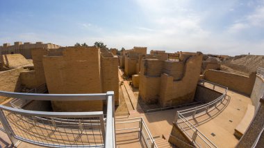 Gökyüzünün altında yeniden inşa edilmiş duvarları olan antik Babil harabelerinin panoramik görüntüsü.
