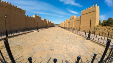 Açık mavi gökyüzünün altında yüksek tuğlalı duvarlarla çevrili antik taş patika..