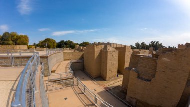 Açık mavi gökyüzünün altında taş duvarları ve yolları olan antik kalıntılar..