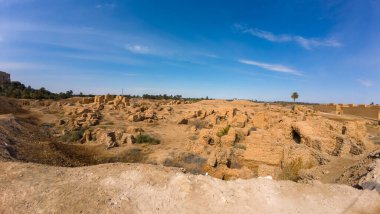 Açık mavi gökyüzünün altında, çöl manzarasında antik kalıntılar..