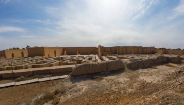 Mavi gökyüzünün altında yeniden inşa edilmiş bir duvarı olan antik kalıntıların panoramik görüntüsü.