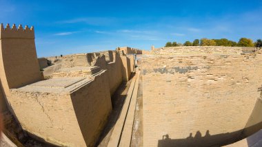 Açık mavi gökyüzünün altında yüksek tuğlalı duvarları olan antik kalıntılar, tarihi mimariyi gözler önüne seriyor..