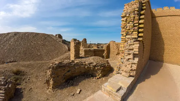 Temiz mavi bir gökyüzünün altında eski tuğla kalıntıları kısmen ayakta duran duvarlar ve dağınık enkazlar ile kıraç bir araziyle çevrili..