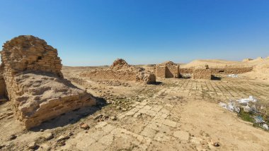 Açık mavi gökyüzünün altında, çöl manzarasında antik kalıntılar..