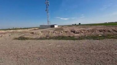 Uçsuz bucaksız, açık bir arazi, kuru, çorak arazi ve açık mavi gökyüzünün altında yeşil çimenler..