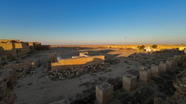 Temiz mavi gökyüzünün altında, dağılmış taş sütunları ve yapıların kalıntılarıyla çöl manzarasında antik kalıntılar..