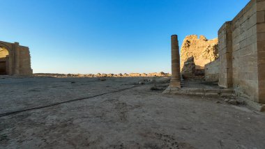 Açık mavi gökyüzüyle çöl manzarasında antik kalıntılar..