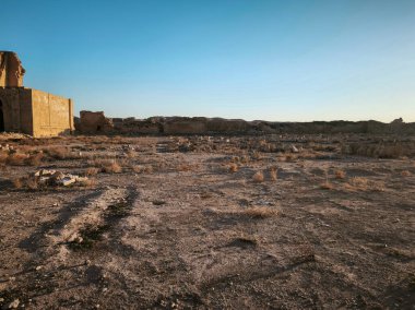 Temiz mavi gökyüzünün altında antik kalıntıları olan çorak bir çöl manzarası..