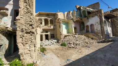 Yıkık dökük duvarları ve enkazı açık mavi gökyüzü altında harap olmuş, savaştan zarar görmüş bir bina..