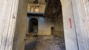 Terk edilmiş, harap olmuş bina döküntüleri ve soyulmuş boyalarla dolu..