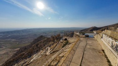 Dağın tepesinden manzaralı bir manzara engin bir manzaraya bakan virajlı yollar ve kayalık arazi berrak bir gökyüzünün altında.