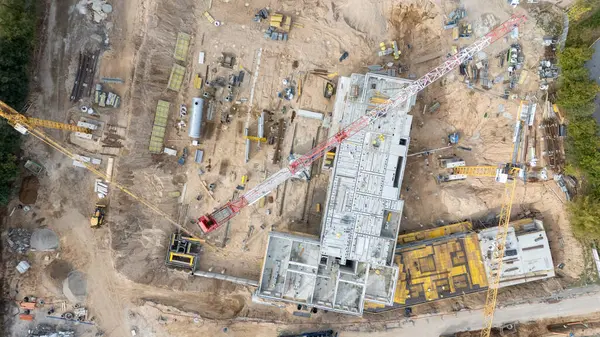 Vinçlerle ve inşaat malzemeleriyle büyük bir inşaat alanının havadan görüntüsü.