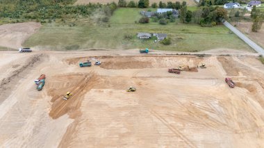 Arazi derecelendirme üzerinde çalışan ağır makineli bir inşaat alanının havadan görüntüsü.