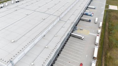 Birden fazla yükleme limanı ve park etmiş kamyonları olan büyük bir sanayi deposunun havadan görüntüsü..