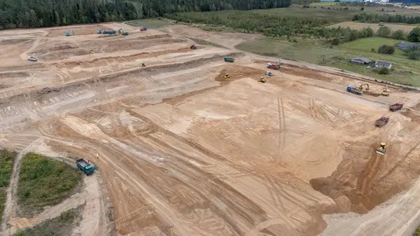 Arazi derecelendirme ve kazılarda çalışan ağır makineler ve araçlarla büyük bir inşaat alanının havadan görüntüsü.