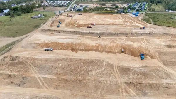 Ağır makineleri ve araçları olan büyük bir inşaat alanının havadan görüntüsü.