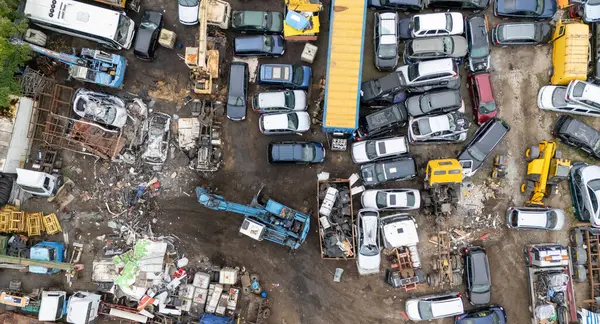 Çeşitli araçlar ve makinelerle dağınık bir hurdalığın hava görüntüsü.