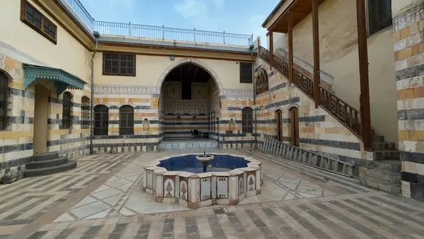 Merkezi bir fıskiyenin bulunduğu tarihi bir avlu. Etrafı taştan duvarlarla çevrili, karmaşık desenlerle dolu. Şam 'ın eski kentinde mimari sergilenen geleneksel ve kültürel öğelerin harmanlanması