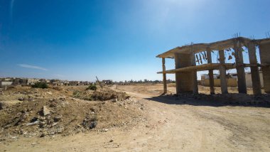 Terk edilmiş, kısmen inşa edilmiş, temiz mavi gökyüzünün altındaki çorak, tozlu bir arazide. Suriye 'nin Şam Jobar ilçesinde