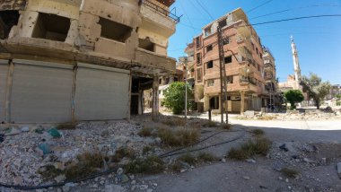 Hasarlı binalar ve enkazlarla harap olmuş bir şehir caddesi. Suriye 'nin Şam Jobar ilçesinde