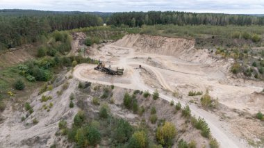 Ormanla çevrili bir kum ocağının havadan görünüşü, makineler çalışıyor..