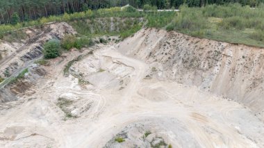 Açıkta kalan toprak ve çevreleyen yeşilliklerin bulunduğu bir kum ocağının havadan görünüşü..
