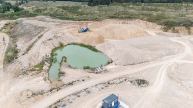 Küçük bir gölet ve makineli bir kum ocağının havadan görünüşü.