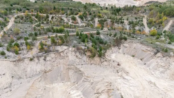 Açıkta kalmış toprak ve seyrek bitki örtüsü olan bir kum ocağının havadan görünüşü.