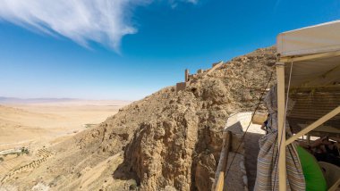 Çölün manzarası. Kayalık bir tepe ve çadır sığınağı var..