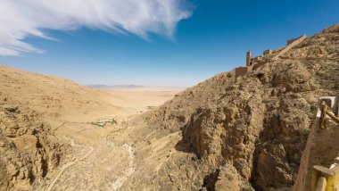 Çölün manzaralı manzarası kayalık tepeler ve açık mavi gökyüzünün altındaki tarihi bir kale..