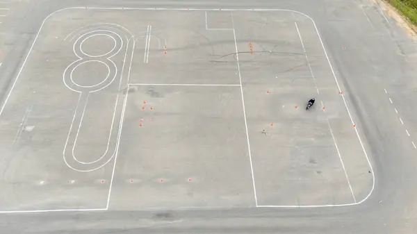 İşaretli şeritler ve koniler ile bir sürüş parkurunda uçan bir motosiklet görüntüsü.