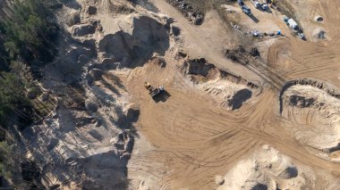 Ağaçlarla çevrili ağır makineli bir kum ocağının havadan görünüşü..