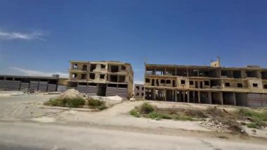 Açık mavi gökyüzünün altında bitmemiş binaları olan terk edilmiş bir şantiye. Kırsal Suriye