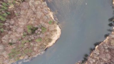 Küçük bir adası ve çevresindeki ormanı olan dolambaçlı bir nehrin havadan görünüşü..