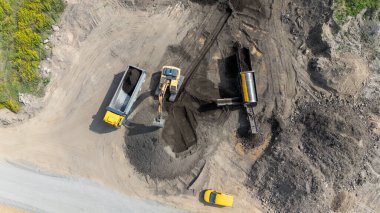 Kazıcının çöp kamyonu yüklediği inşaat alanının havadan görüntüsü.