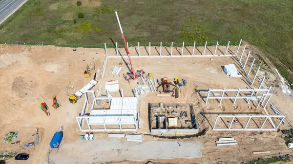 Vinçleri ve yapı iskeleti olan bir inşaat alanının havadan görüntüsü.