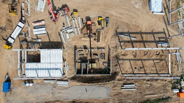 Vinçlerin, inşaat malzemelerinin ve işçilerin bulunduğu bir inşaat alanının havadan görüntüsü..