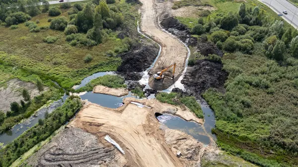 İnşaat alanının havadan görüntüsü, kazıcı nehrin yakınındaki toprak bir yolda çalışıyor..