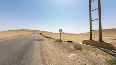 Saatte 50 km hız sınırı ve açık mavi gökyüzü olan çöl yolu..