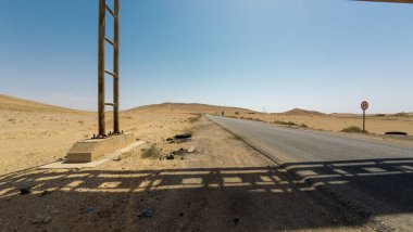 Açık mavi gökyüzü ve uzak tepeleri olan çöl yolu..