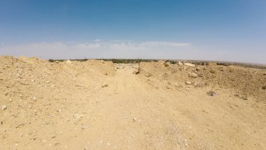 Açık mavi gökyüzünün altında toprak yığınları olan çöl manzarası..