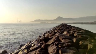 Paiton sahilinin arka planındaki dalgada Paiton buhar santrali binasının